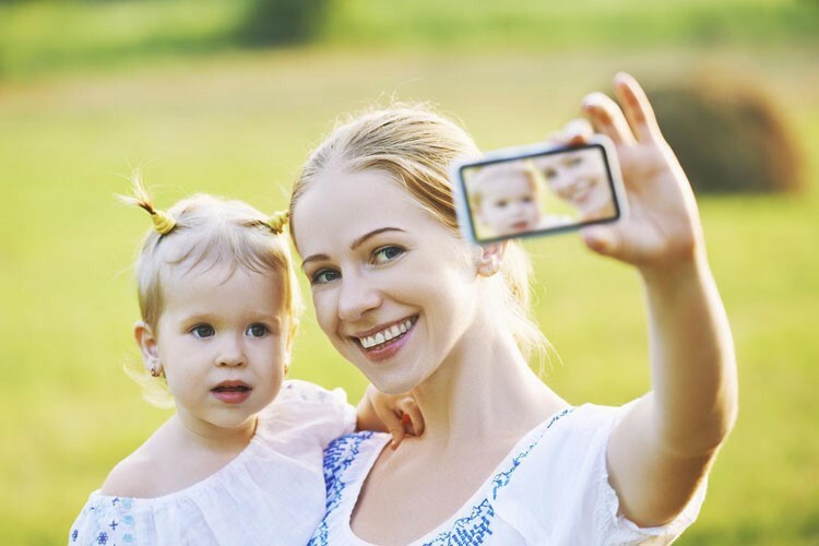 Мама фотографируется с ребенком на смартфон